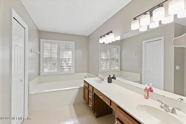 a bathroom with a tub a sink and mirror