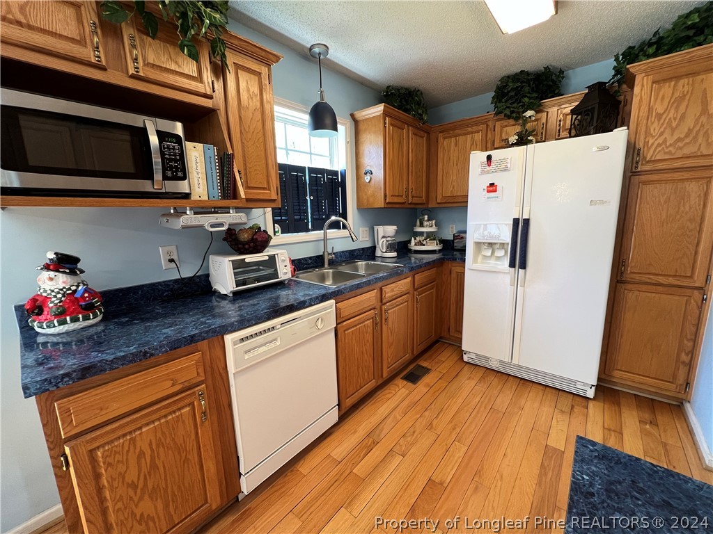 2196 Post Office Road Sanford, NC 27330 - Photo 11 of 21 a kitchen with stainless steel appliances granite countertop a refrigerator a stove top oven a sink dishwasher and white cabinets with wooden floor