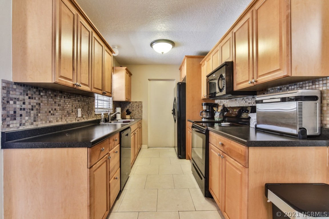 700 Green Road New Smyrna Beach, FL 32168 - Photo 14 of 37 a kitchen with stainless steel appliances granite countertop a stove a sink and a microwave