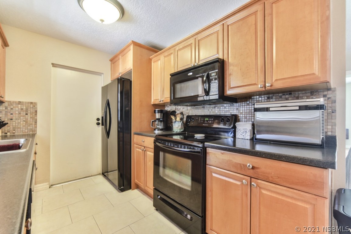 700 Green Road New Smyrna Beach, FL 32168 - Photo 15 of 37 a kitchen with stainless steel appliances granite countertop a refrigerator stove and sink