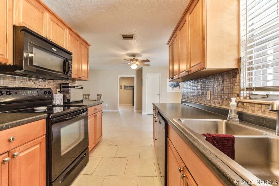 700 Green Road New Smyrna Beach, FL 32168 - Photo 17 of 37 a kitchen with stainless steel appliances granite countertop a sink a stove and microwave