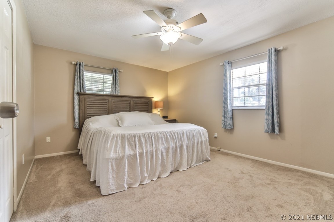 700 Green Road New Smyrna Beach, FL 32168 - Photo 21 of 37 a spacious bedroom with a bed and a chandelier