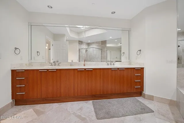 a large kitchen with a large counter top a sink stainless steel appliances and cabinets