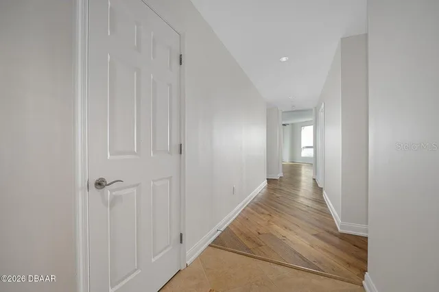 a view of an empty room with a window and wooden floor