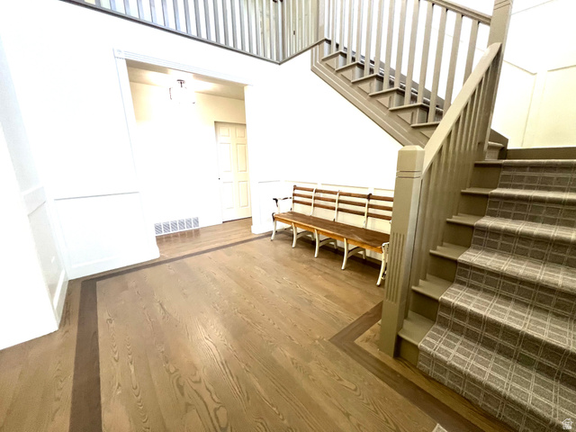 812 East Bates Cyn Road Tooele, UT 84074 - Photo 7 of 144 Entryway featuring wood-finish flooring with a dark border inlay, wainscoting details, and a staircase with patterned carpeting and painted wood railings