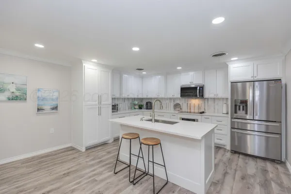 a kitchen with a sink a stove a refrigerator and white cabinets with wooden floor