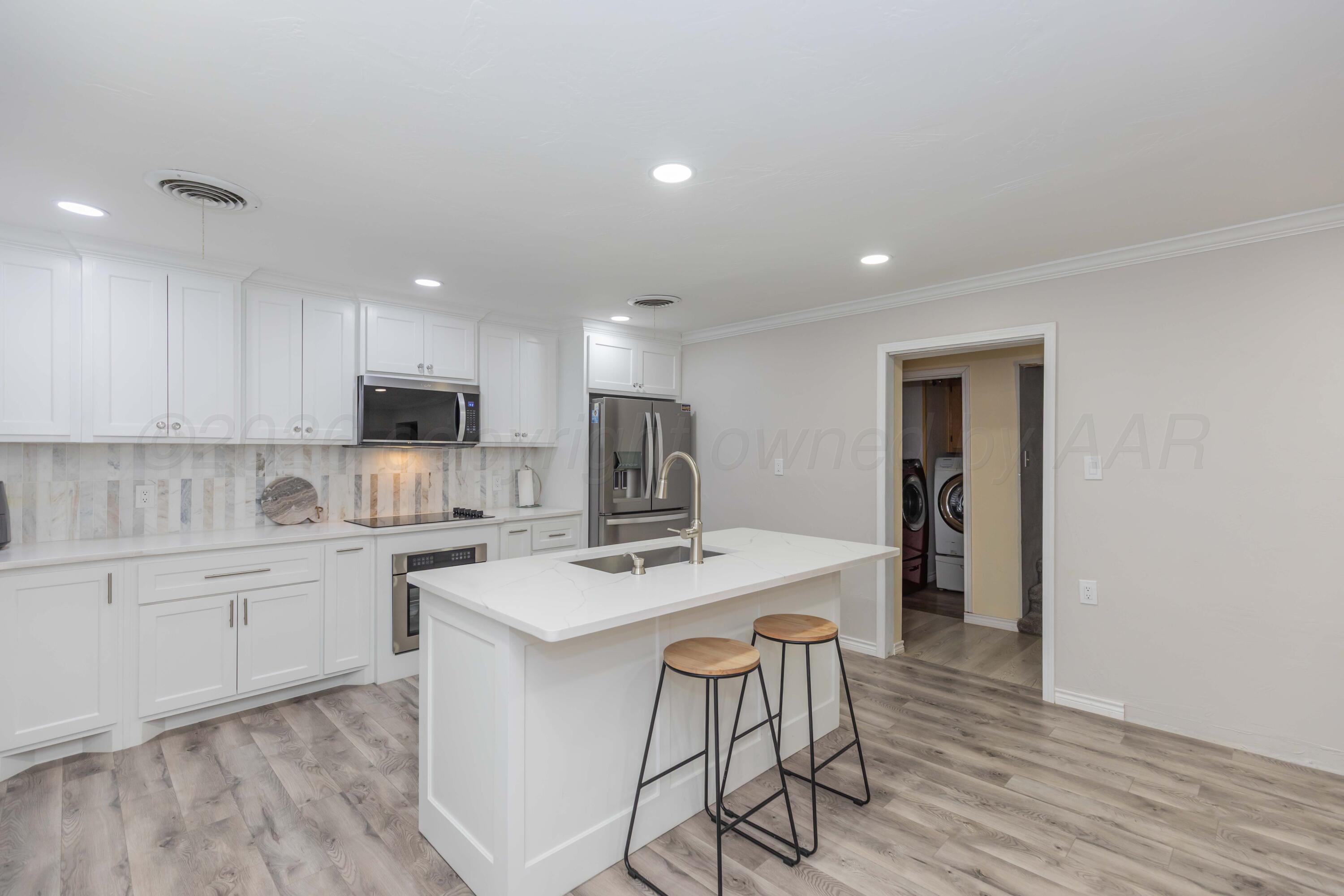 905 North Travis Street Amarillo, TX 79107 - Photo 13 of 42 a kitchen with a sink a stove a refrigerator and white cabinets with wooden floor