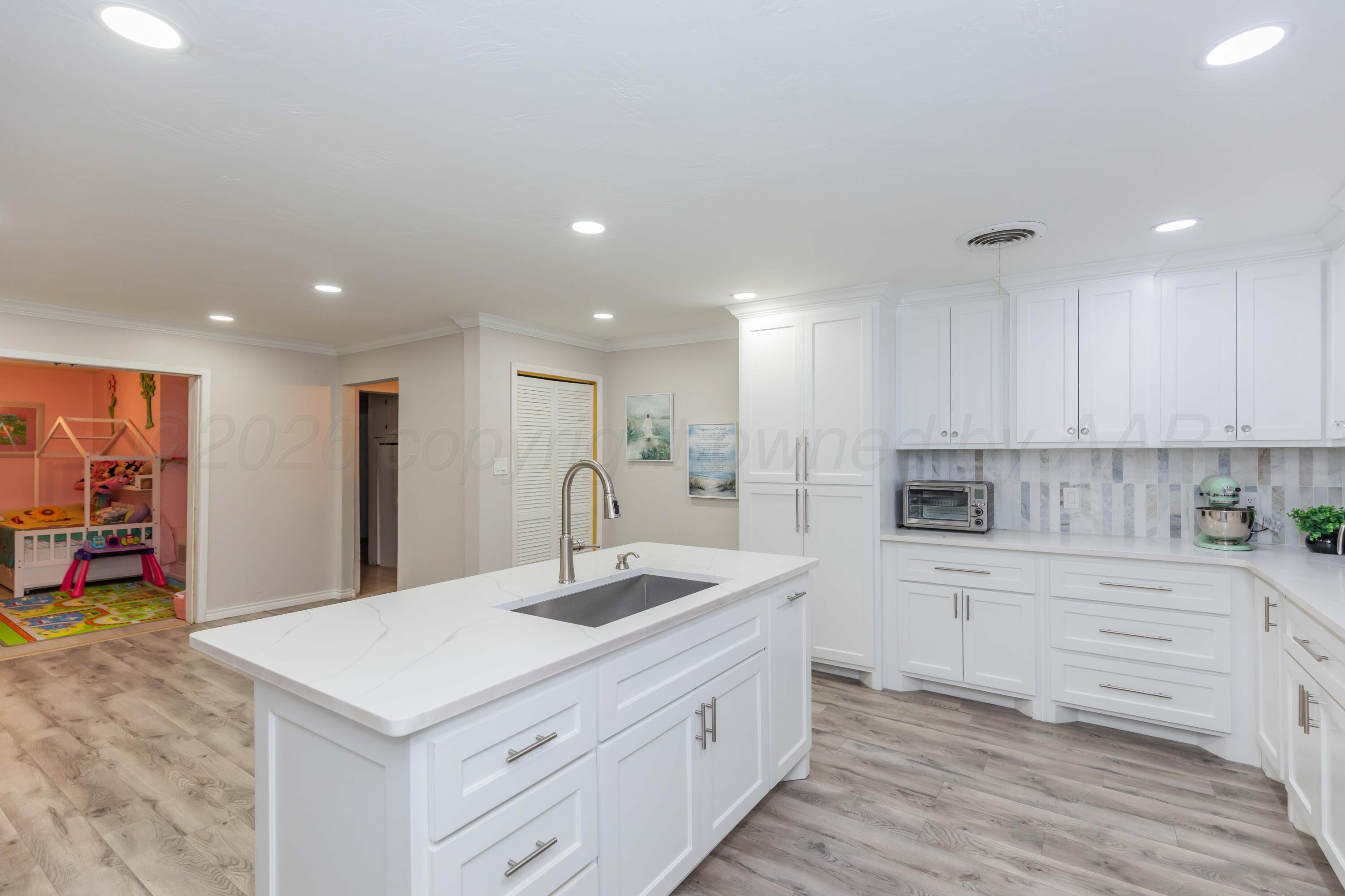 905 North Travis Street Amarillo, TX 79107 - Photo 15 of 42 a kitchen with white cabinets sink and center island