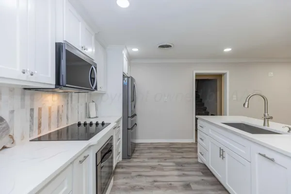 a large kitchen with kitchen island a stove a table and chairs in it