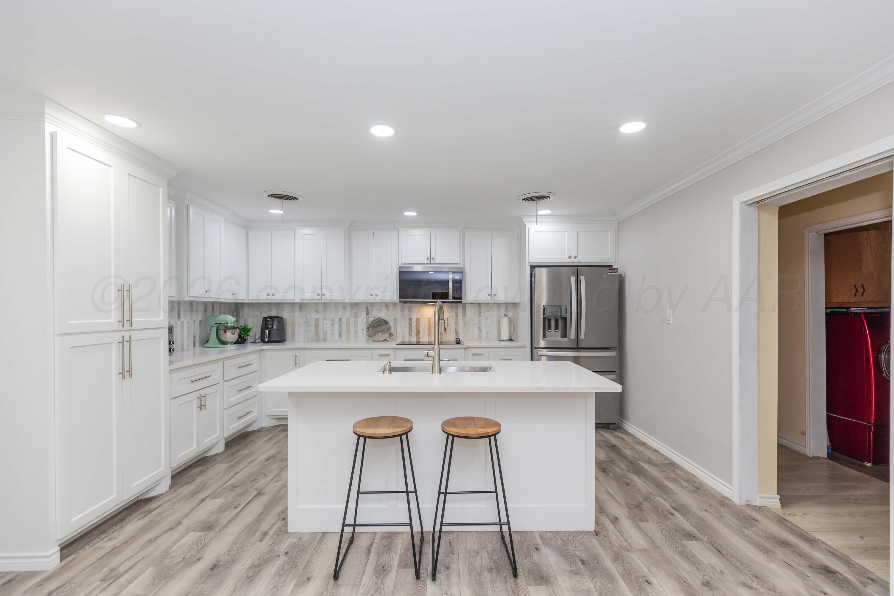 905 North Travis Street Amarillo, TX 79107 - Photo 17 of 42 a large kitchen with kitchen island a stove a table and chairs in it