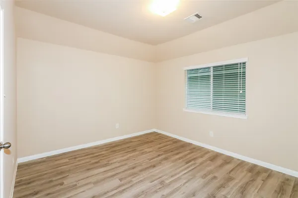 an empty room with wooden floor and a window