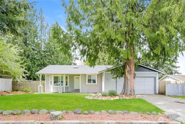 a front view of a house with a garden and trees