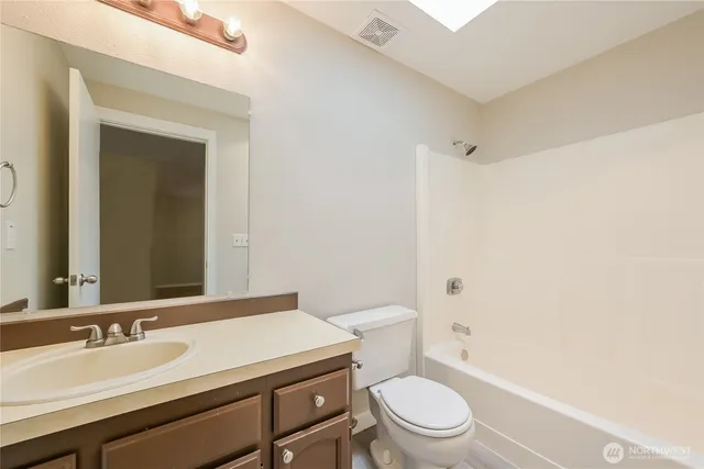 a bathroom with a granite countertop toilet a sink a mirror and a shower