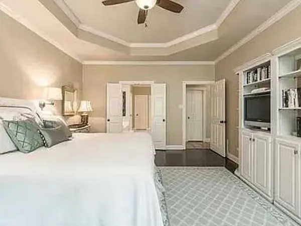 a large bedroom with a bed and a flat tv screen on dresser