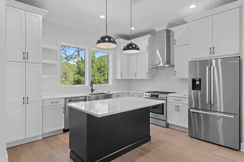 a kitchen with stainless steel appliances granite countertop a sink dishwasher a refrigerator and a oven with wooden floor