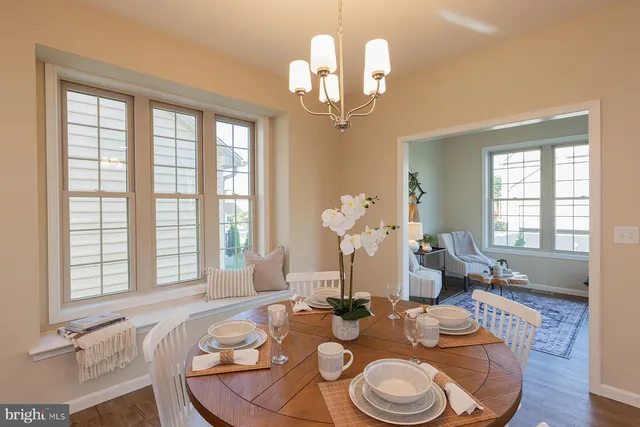 a dining room with wooden floor a chandelier a glass table and chairs
