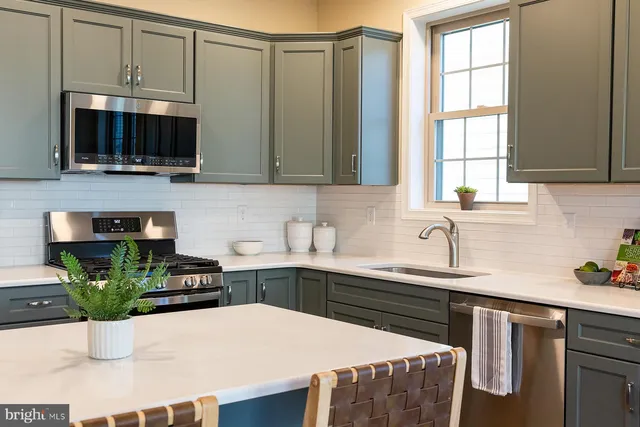 a kitchen with stainless steel appliances a sink a stove a microwave a sink and cabinets