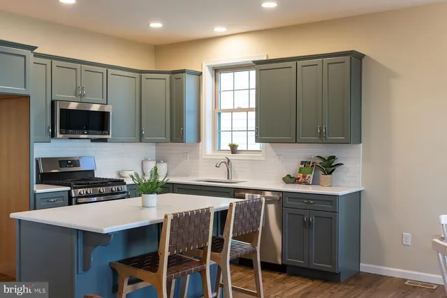 a kitchen with stainless steel appliances a stove a sink a microwave a refrigerator and cabinets