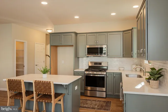 a kitchen with stainless steel appliances a stove a sink cabinets and a dining table