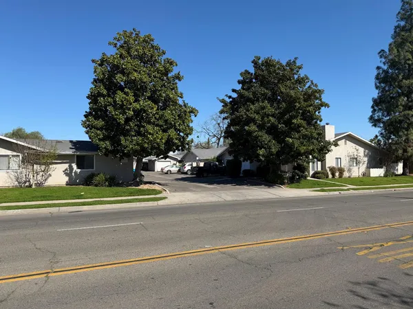 a front view of a house with a yard covered with snow and trees