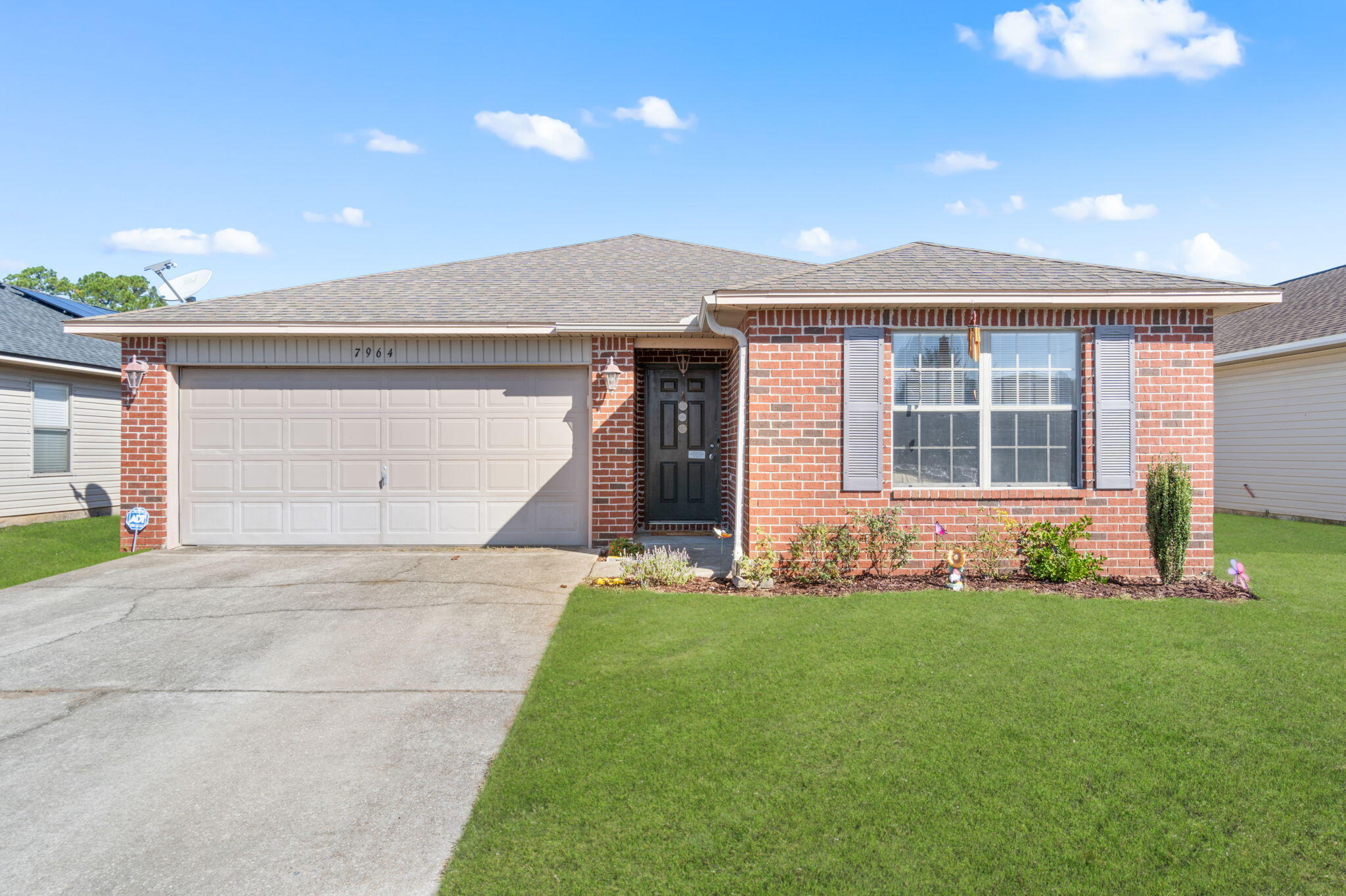7964 Promise Creek Road Navarre, FL 32566 - Photo 2 of 43 a front view of a house with a garden and yard