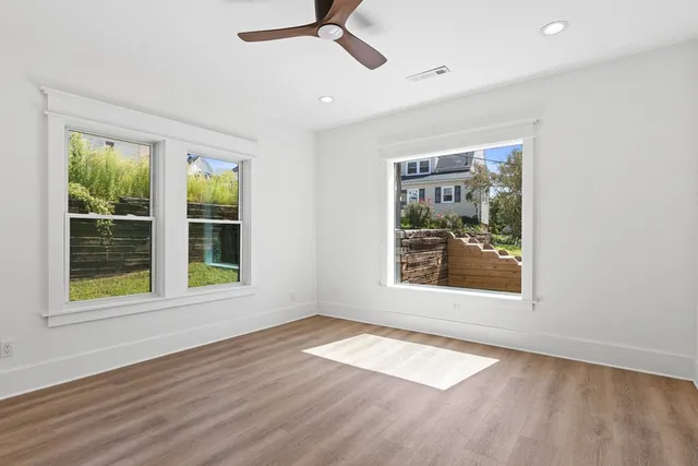 an empty room with wooden floor and windows