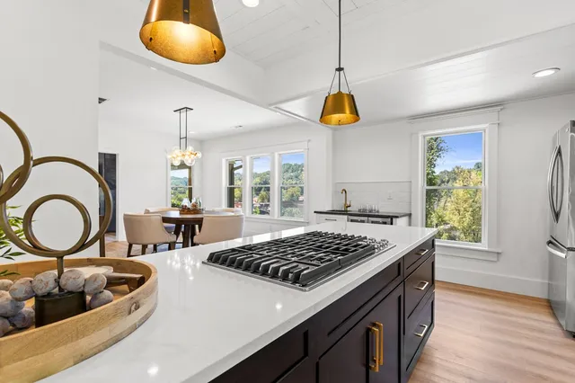 a kitchen with a stove a sink a kitchen island a counter space and windows
