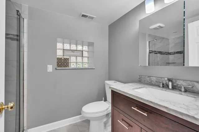 a bathroom with a granite countertop toilet sink and mirror