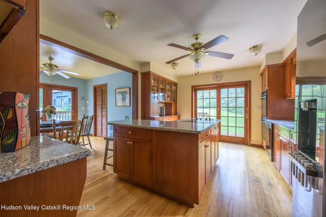 a living room with stainless steel appliances granite countertop furniture wooden floor and a kitchen view