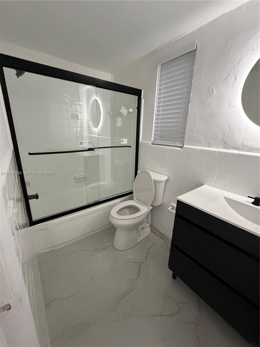324 Surfside Boulevard, Unit 7 Surfside, FL 33154 - Photo 2 of 14 a bathroom with a toilet a sink and a mirror