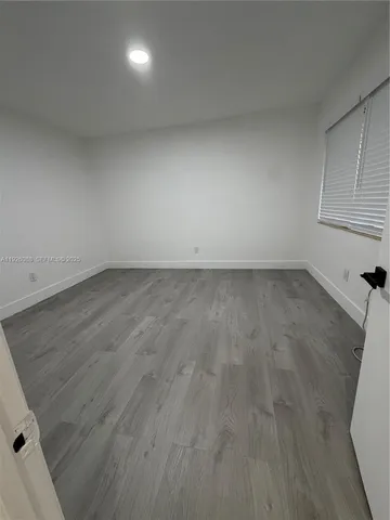 an empty room with wooden floor and windows in it