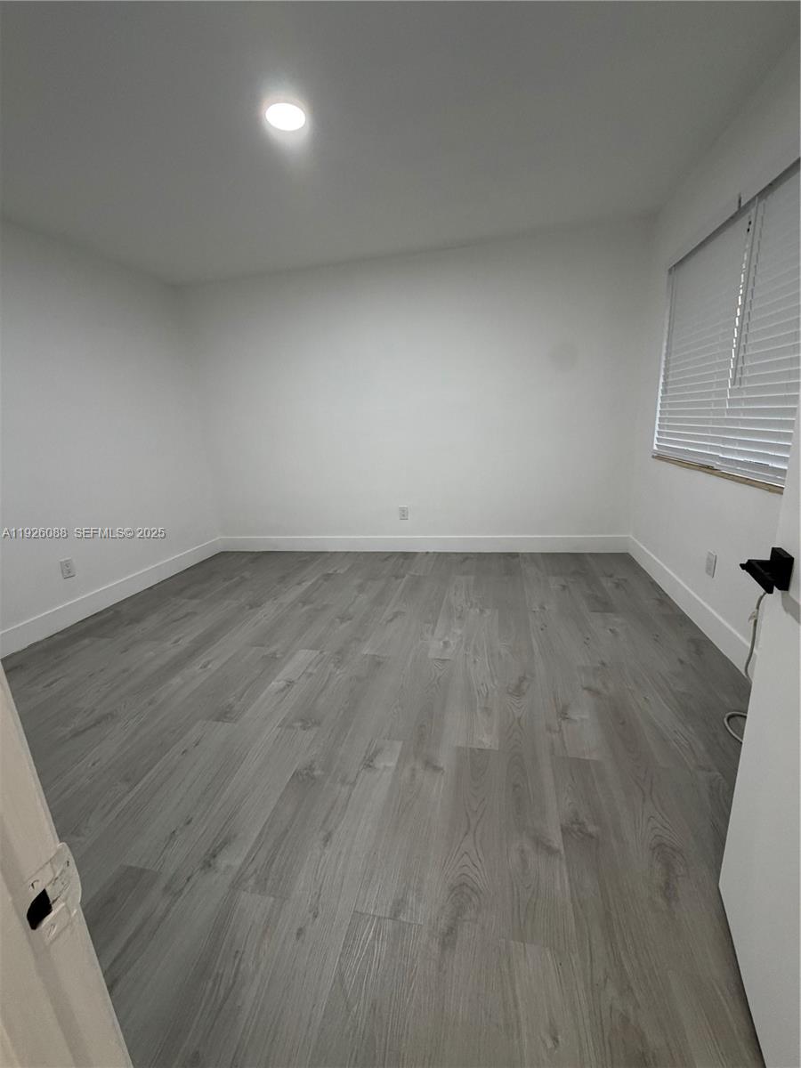 324 Surfside Boulevard, Unit 7 Surfside, FL 33154 - Photo 5 of 14 an empty room with wooden floor and windows in it