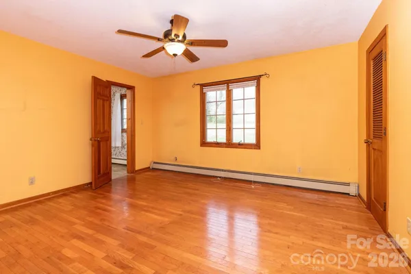 a view of empty room with wooden floor and fan