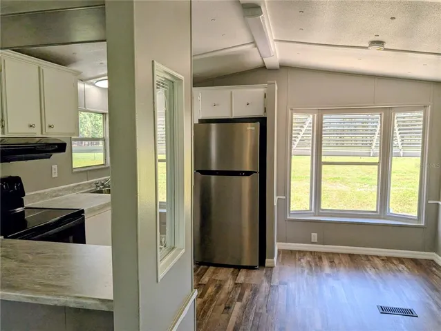 a view of a kitchen with wooden floor and a refrigerator
