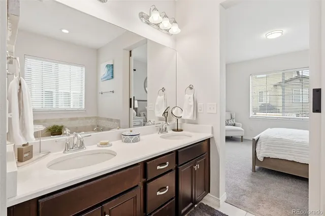 a en suite bathroom with double vanity sinks a large mirror and a bathtub