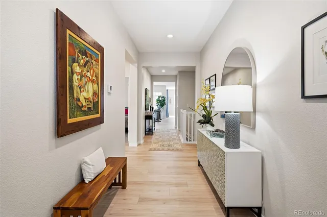 a view of a hallway with couches and dining table with wooden floor