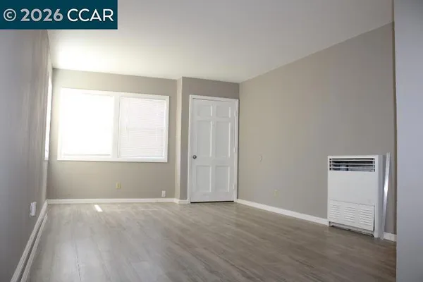 a view of an empty room with wooden floor and a window