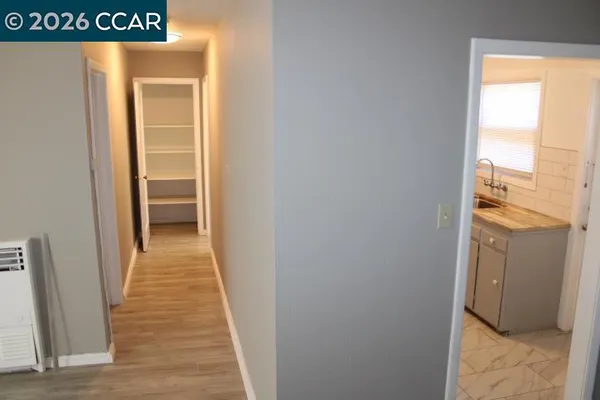 a view of a hallway with wooden floor and a bathroom