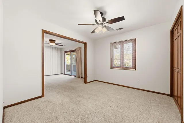 an empty room with windows and fan