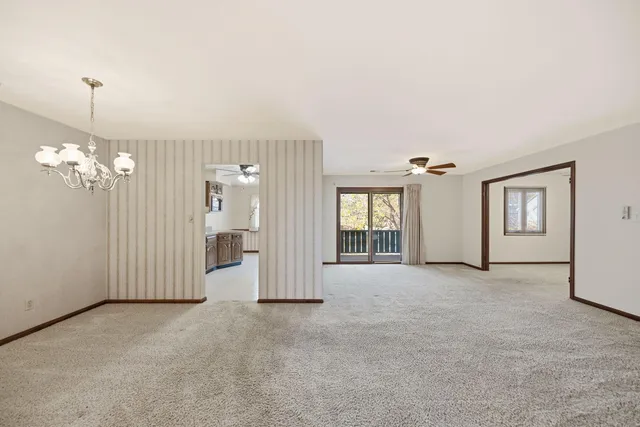 a view of a livingroom with a chandelier fan and windows