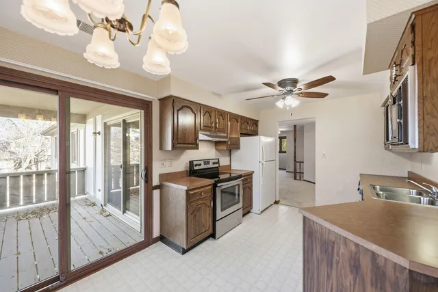 a kitchen with kitchen island granite countertop a sink appliances cabinets and a large window