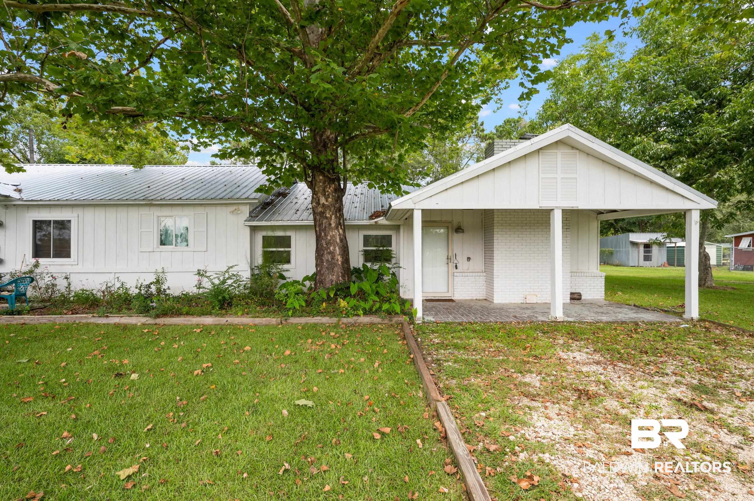 24663 Chestnut Street Elberta, AL 36530 - Photo 1 of 22 White siding exterior with a metal roof and a covered entryway