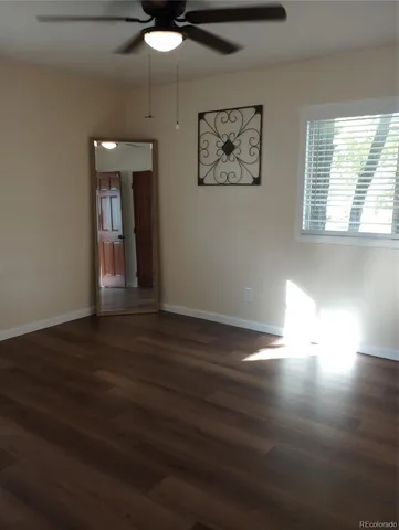 a view of an empty room with wooden floor and a window