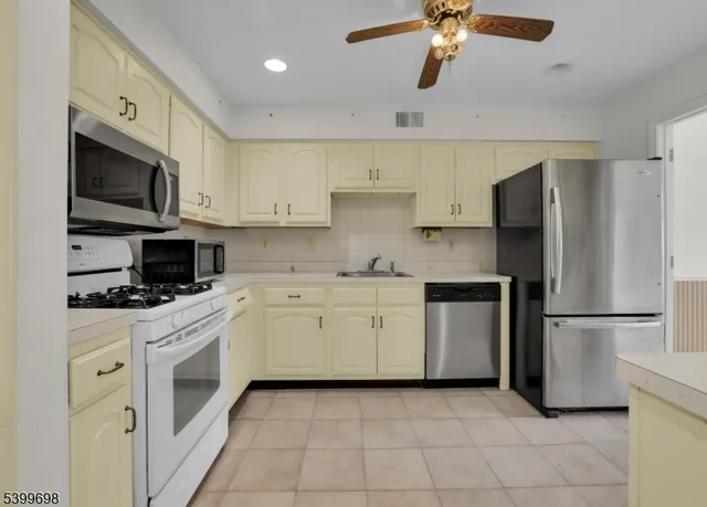 a kitchen with stainless steel appliances granite countertop a refrigerator a stove a microwave oven with white cabinets