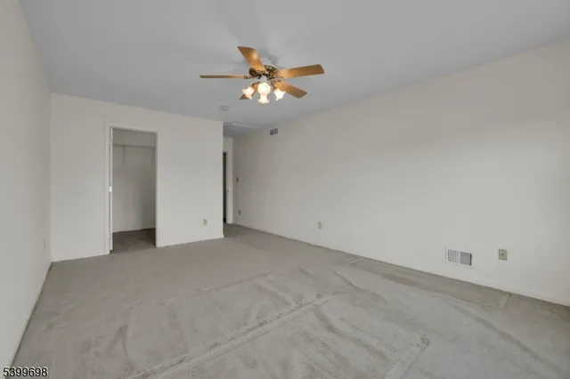 an empty room with a chandelier fan and windows