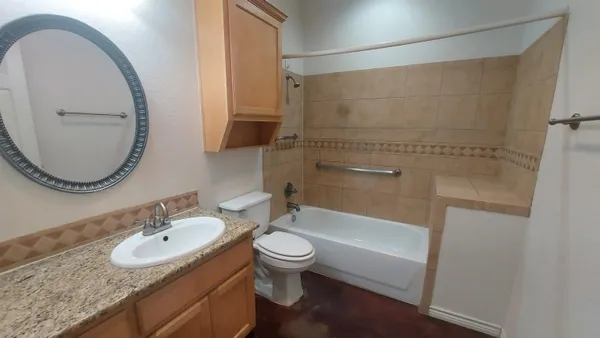 a bathroom with a granite countertop sink a toilet and a mirror