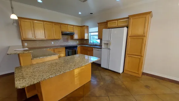 a kitchen with stainless steel appliances granite countertop a refrigerator and a stove