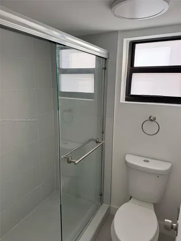 a white toilet sitting next to a shower