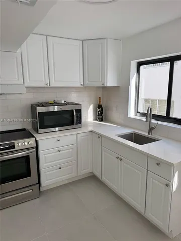a kitchen with white cabinets and white appliances