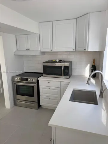 a kitchen with granite countertop white cabinets and stainless steel appliances